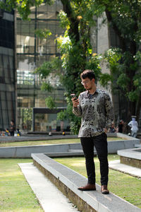  young man in batik shirt uses smartphone at a park