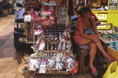 Full length of woman sitting at market stall
