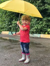 Full length of cute boy standing in rain