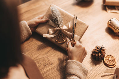 Close-up of hands wrapping gifts for christmas, stylish decoration, vintage, warm colors