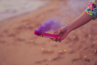 Cropped hand holding distress flare at beach