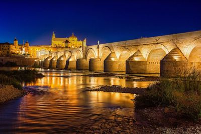Illuminated bridge against clear sky at night