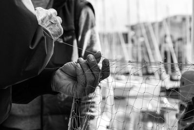 Cropped hand of fisherman sewing fishing net