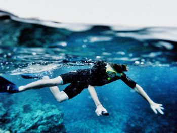 Full length of scuba diver swimming in blue sea