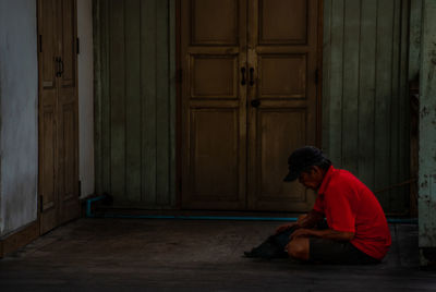 Side view of man sitting outside building