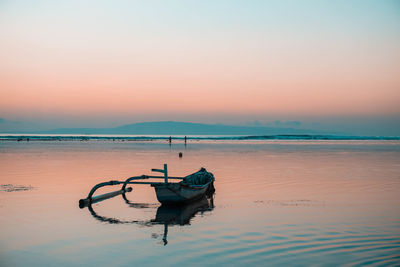 Boat moored on sea against sky during sunset