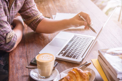 Low section of woman holding coffee cup on table