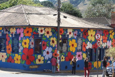 People walking on street against multi colored buildings in city