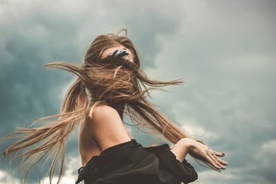Woman with tousled hair against cloudy sky