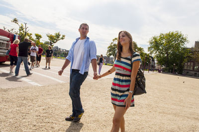 Full length of smiling young woman standing against sky