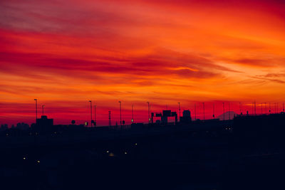 Silhouette of factory against orange sky