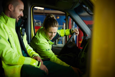 Paramedics discussing while sitting in ambulance in parking lot