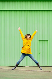 Full length of young woman jumping against wall