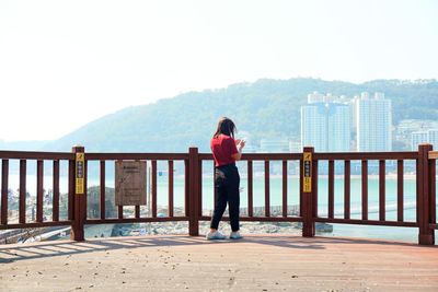 Rear view of man standing on railing against mountain