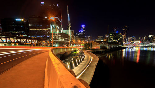 Illuminated bridge over river in city at night