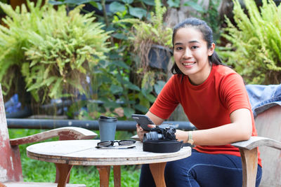 Portrait of smiling young woman sitting on table