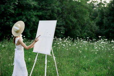 Woman holding umbrella standing on field