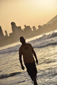 Rear view of man standing on beach during sunset