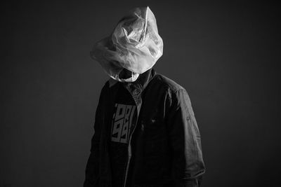 Man wearing hat standing against black background