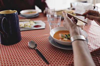 Cropped image of senior couple sitting with food at dining table