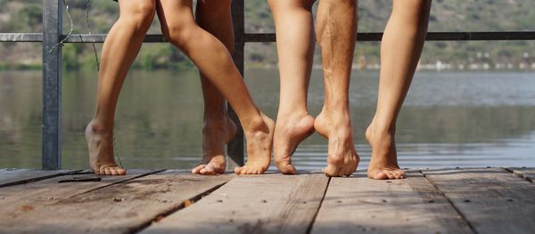 Low section of people on pier over lake