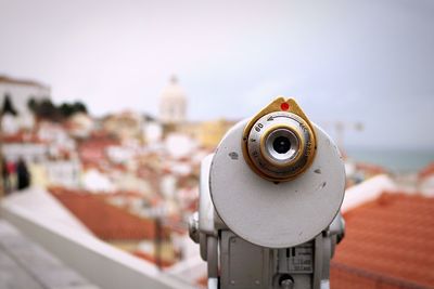 Close-up of coin-operated binoculars against cityscape