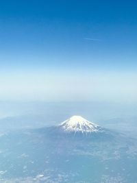 Aerial view of snowcapped mountain against blue sky