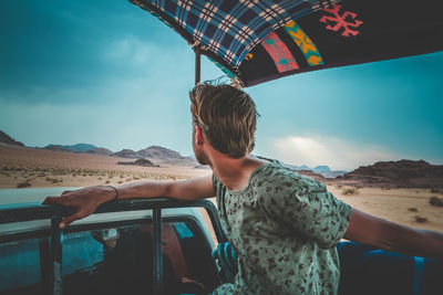 Man sitting in vehicle against land