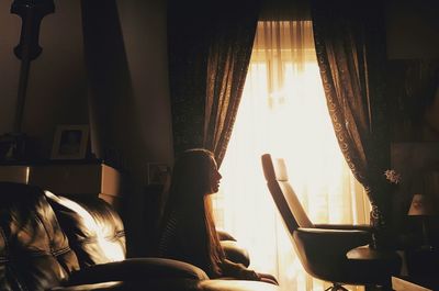 Side view of thoughtful woman sitting on sofa at home