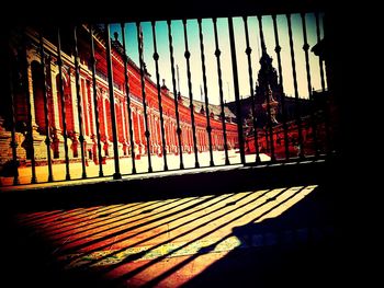 Shadow of railing on city street against sky