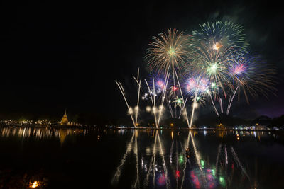 Firework display over lake at night