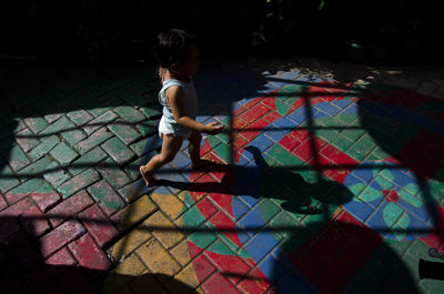 High angle view of girl walking on multi colored tiled floor