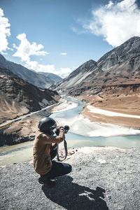 Man photographing on mountains against sky