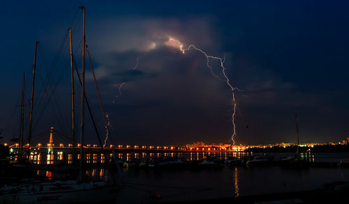 Illuminated bridge over river against sky at night