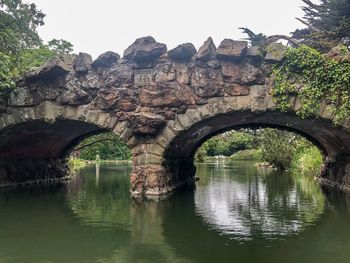 Arch bridge over lake against sky