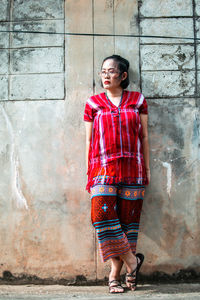 Full length of young woman standing against wall