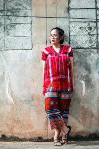 Full length of young woman standing against wall