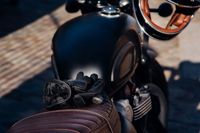 Close-up of gloves on motorcycle parked outdoors