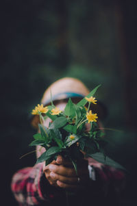 Close-up of hand holding flowering plant