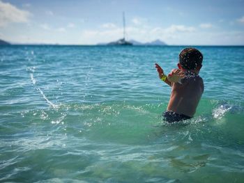 Boy standing in sea against sky