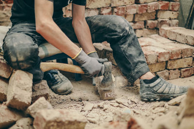 A young man cleans bricks with an axe.