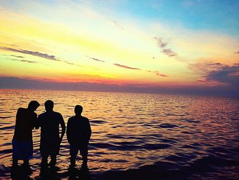 Silhouette men standing on beach against sky during sunset