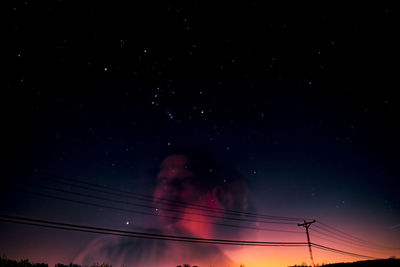 Low angle view of electricity pylon against sky at night