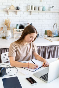 Young woman using mobile phone at table