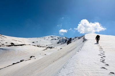 Rear view of man walking on snow covered mountain