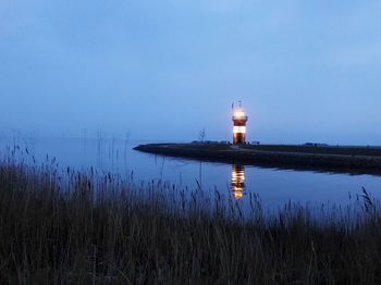 Lighthouse by lake against sky