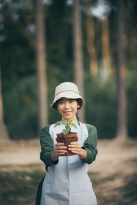 Portrait of man holding camera while standing on field