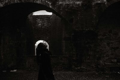 Side view of woman looking up against abandoned building