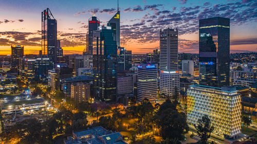 Illuminated buildings in city during sunset