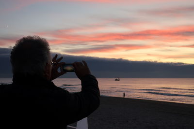 Rear view of man photographing sea